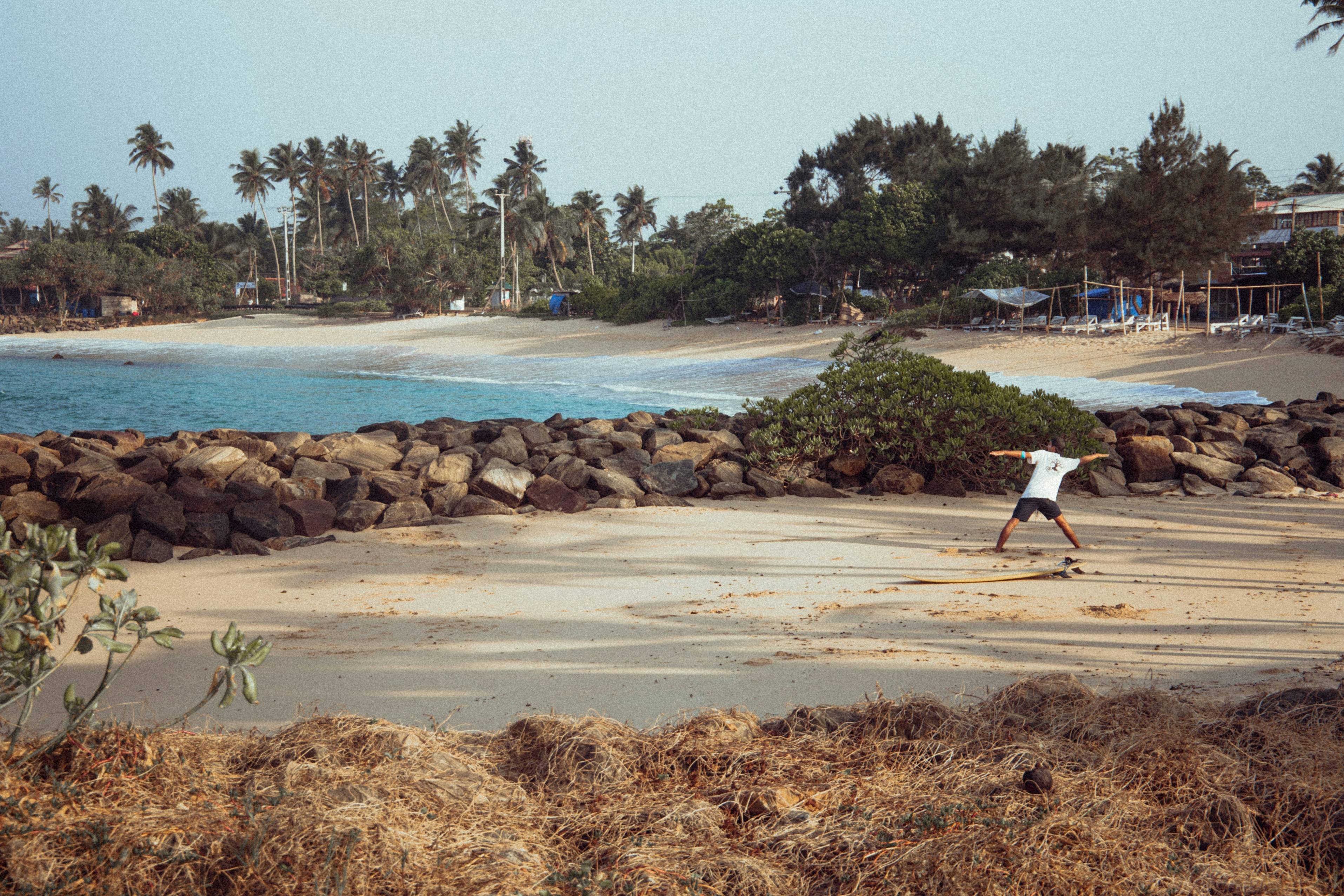 man in white shirt and black pants walking on beach during daytime